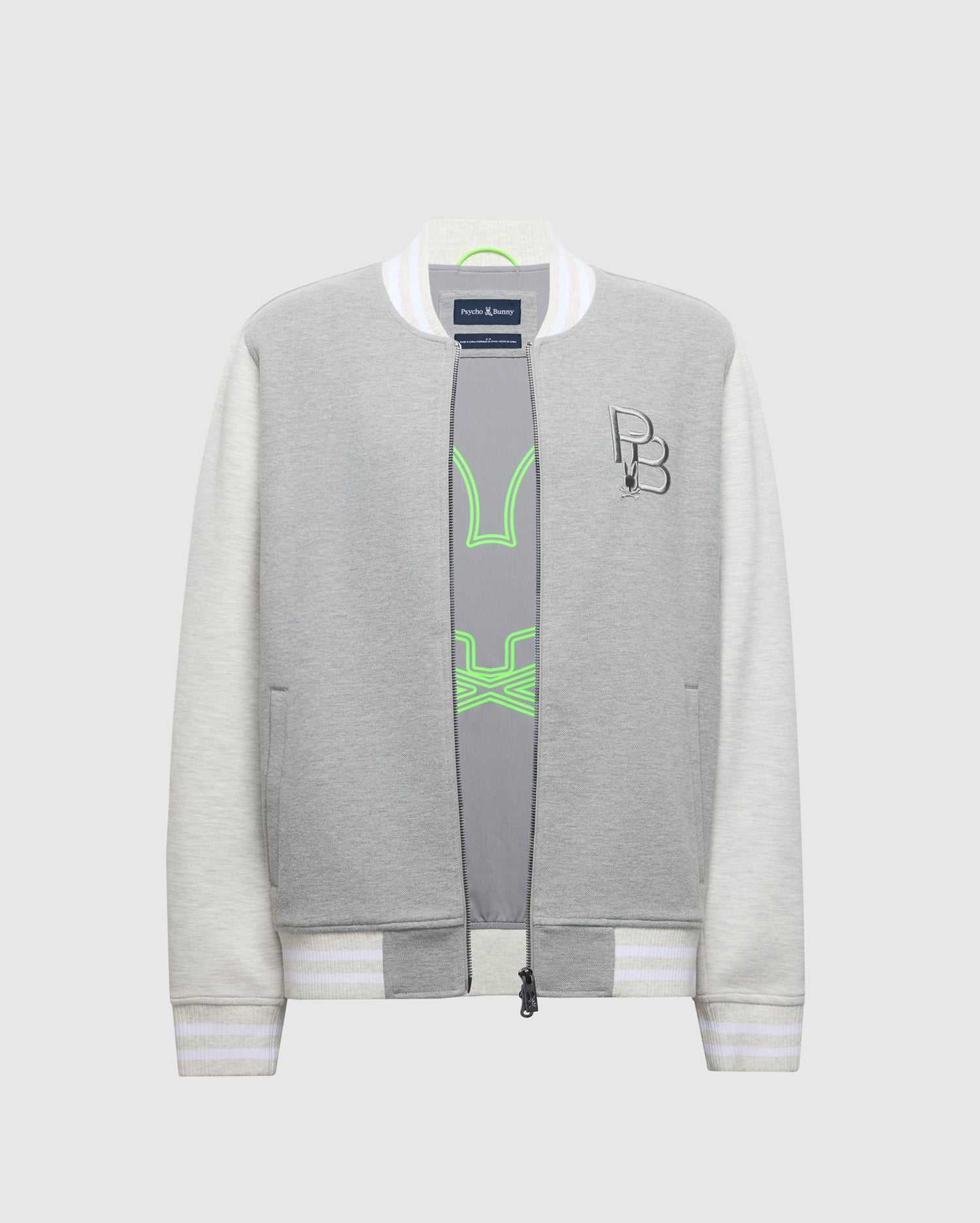 The Psycho Bunny MENS HYDRA COLOR BLOCK KNIT BOMBER (B6J455F200) is a gray and white bomber jacket crafted from a premium cotton blend. It features striped ribbed cuffs, collar, an embroidered Bunny logo on the chest, and reveals a gray top with neon green accents when unzipped.