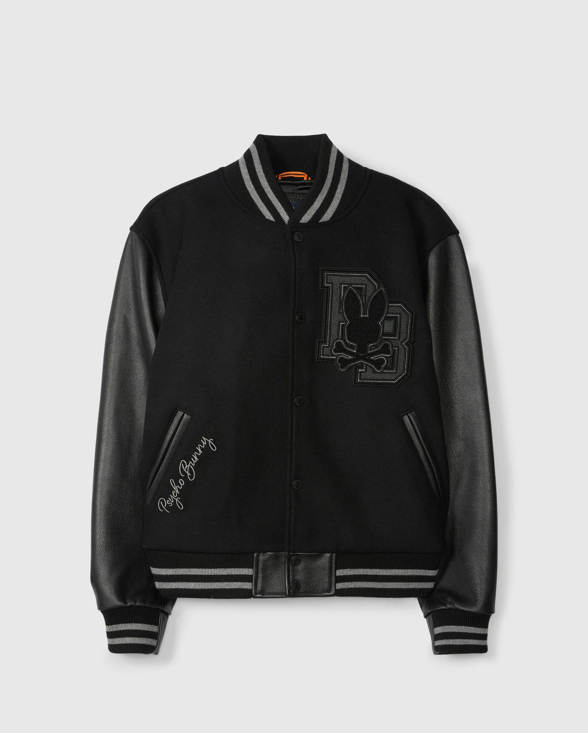 Introducing the Psycho Bunny Men's Brayden Wool Leather Varsity Bomber (B6J876D200), a stylish jacket crafted with a black wool blend and accentuated by leather sleeves. The design features ribbed cuffs and a collar, along with a prominent emblem displaying a stylized rabbit and the initials "DB" on the front. Additionally, one sleeve is elegantly embroidered with "Playboy Bunny.