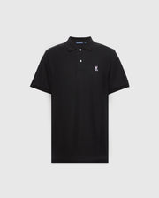 The Psycho Bunny Men's Classic Pique Polo Shirt (B6K001ARPC) is black, made from 100% Pima cotton, and features a small embroidered rabbit and crossbones logo on the left chest. It has a classic collar with a two-button placket adorned with sleek mother-of-pearl buttons against a light gray background.