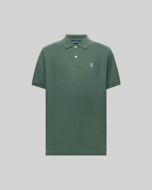 The Psycho Bunny MENS CLASSIC PIQUE POLO - B6K001F200 is a plain green men's polo in soft Pima cotton, with a collar, two buttons, and a small embroidered Bunny logo on the left chest, shown on a light gray background.
