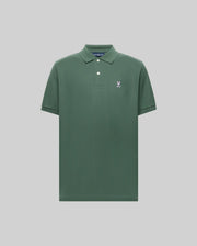 The Psycho Bunny MENS CLASSIC PIQUE POLO - B6K001F200 is a plain green men's polo in soft Pima cotton, with a collar, two buttons, and a small embroidered Bunny logo on the left chest, shown on a light gray background.