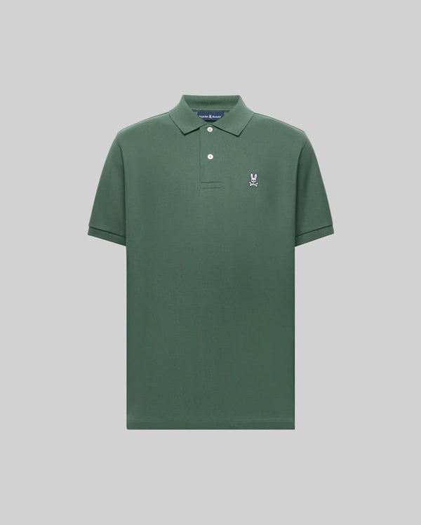 The Psycho Bunny MENS CLASSIC PIQUE POLO - B6K001F200 is a plain green men's polo in soft Pima cotton, with a collar, two buttons, and a small embroidered Bunny logo on the left chest, shown on a light gray background.
