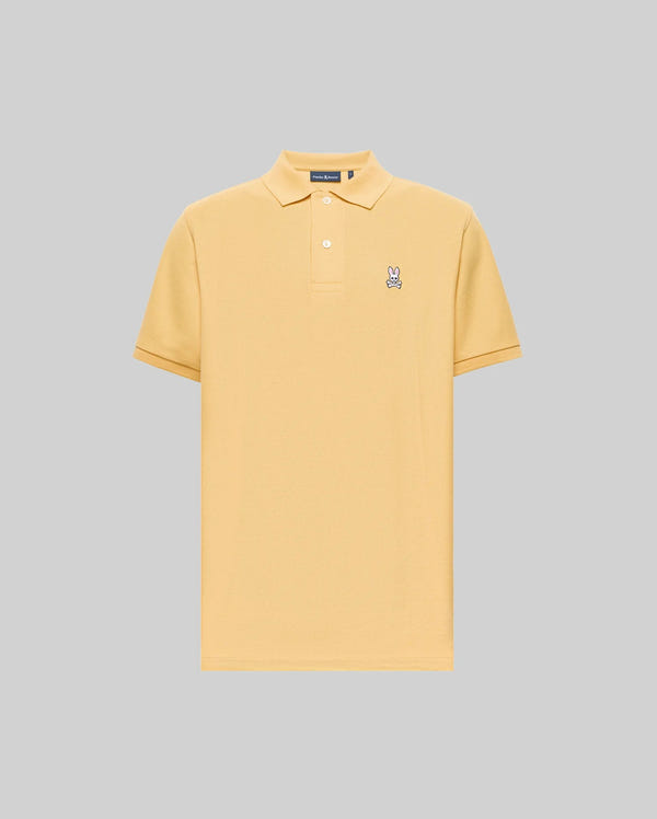 The Psycho Bunny MENS CLASSIC PIQUE POLO - B6K001F200 is a light yellow, short-sleeve Pima cotton polo with a collar, two buttons, and an embroidered Bunny logo on the left chest, set against a plain gray background.