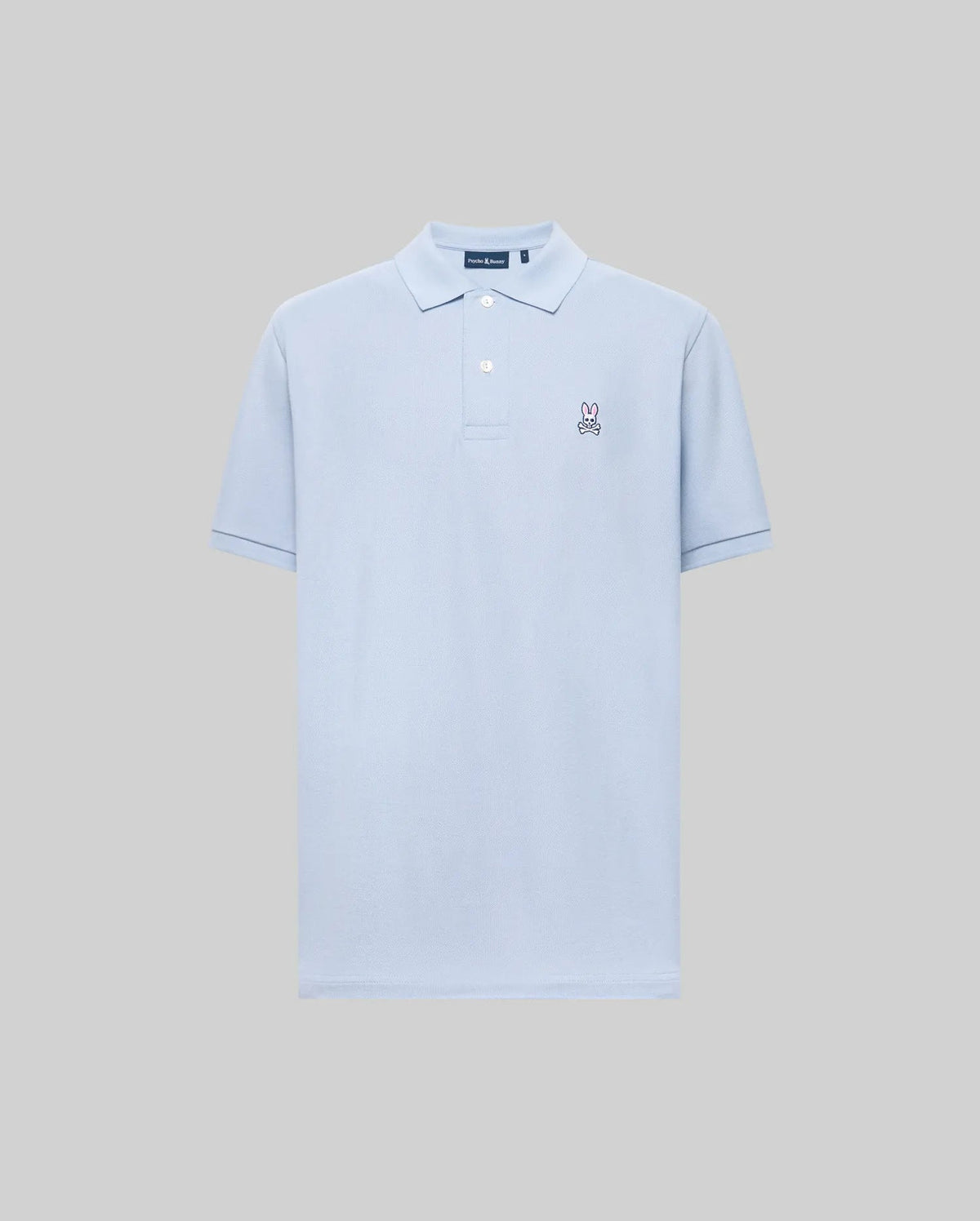 The Psycho Bunny MENS CLASSIC PIQUE POLO (B6K001F200) is a light blue short-sleeved Pima cotton men’s polo with a collar, two buttons, and an embroidered bunny logo on the left chest, shown on a plain gray background.