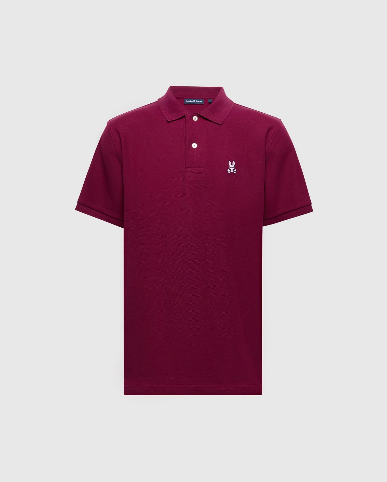 The Psycho Bunny Men's Classic Pique Polo Shirt - B6K001Z1PC features a maroon color crafted from soft Pima cotton, short sleeves, collar with two buttons, and a distinguished embroidered Bunny logo on the left chest on a plain light gray background.