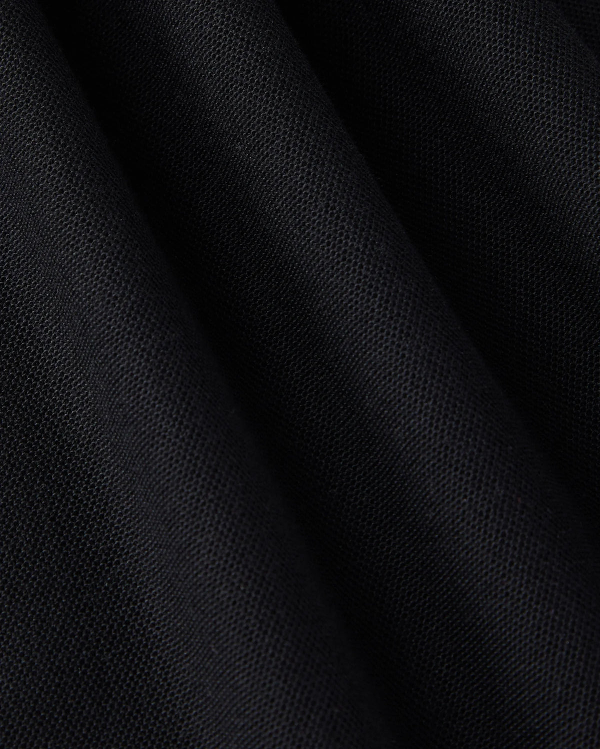 Close-up of a Pima cotton polo fabric with a slightly textured surface and folds. The solid pattern material appears soft, and the folds create subtle shadow variations, enhancing the depth and texture of the MENS EAST HILLS JOHNNY COLLAR POLO SHIRT - B6K331B200 by Psycho Bunny.