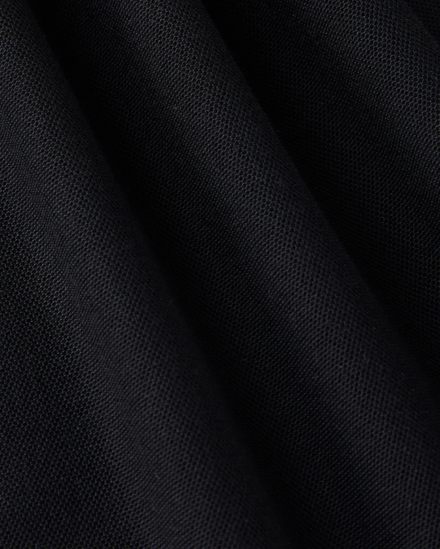 Close-up of a Pima cotton polo fabric with a slightly textured surface and folds. The solid pattern material appears soft, and the folds create subtle shadow variations, enhancing the depth and texture of the MENS EAST HILLS JOHNNY COLLAR POLO SHIRT - B6K331B200 by Psycho Bunny.