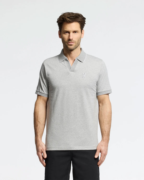 A man with short brown hair and a trimmed beard wears the Psycho Bunny MENS MACKAY JACQUARD JOHNNY COLLAR POLO (B6K408F200) in light gray and black pants, standing against a plain white background.