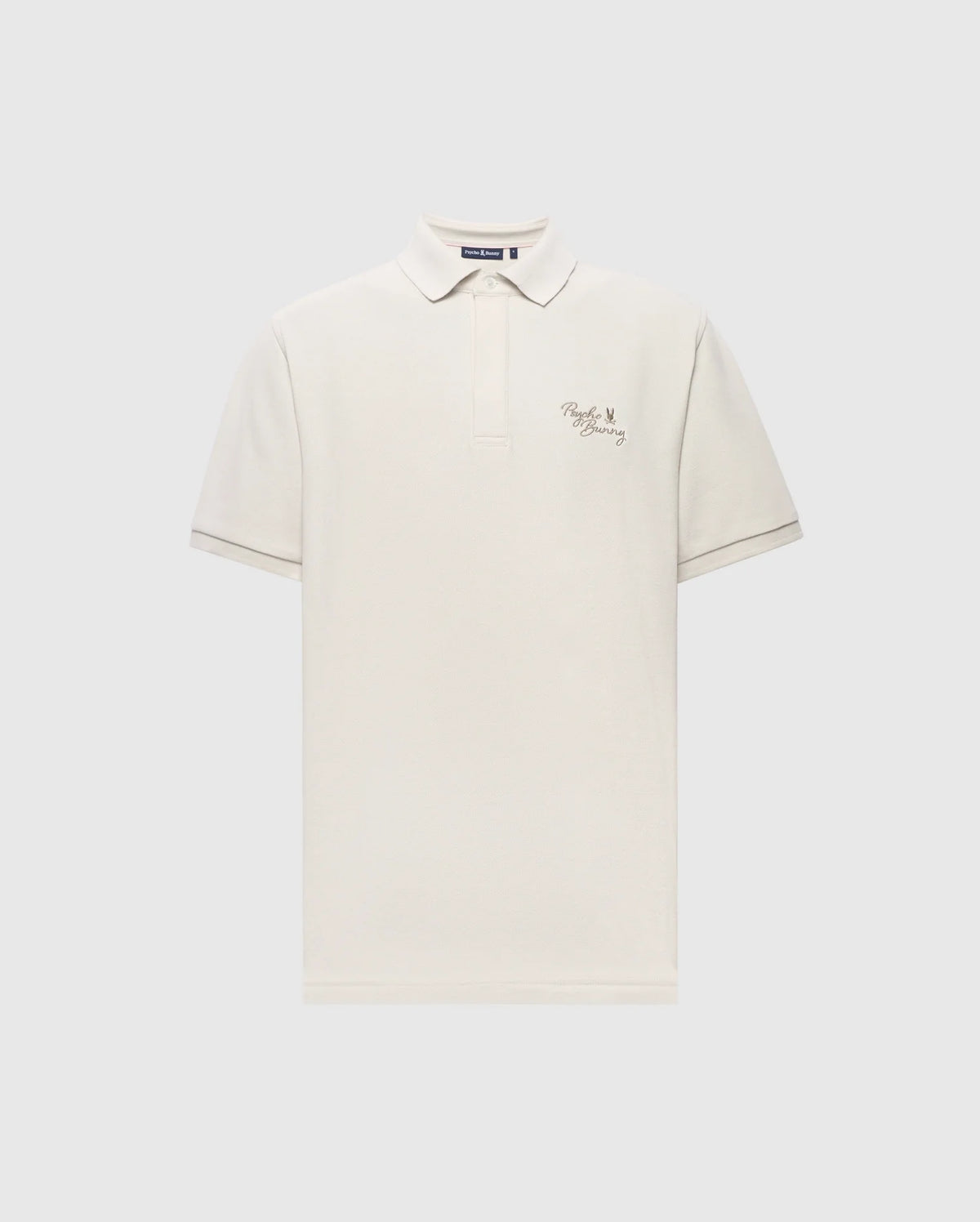 The Psycho Bunny MENS DESERT PIQUE POLO - B6K506F200 is crafted from soft Pima cotton, featuring a white color with a collar and buttoned placket. It showcases text and a small heart design on the left chest against a light gray background, offering timeless style.