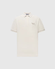 The Psycho Bunny MENS DESERT PIQUE POLO - B6K506F200 is crafted from soft Pima cotton, featuring a white color with a collar and buttoned placket. It showcases text and a small heart design on the left chest against a light gray background, offering timeless style.