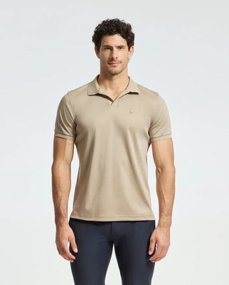 A man with short, curly hair wears a Psycho Bunny MENS BROADWAY PIMA INTERLOCK JOHNNY COLLAR POLO B6K891D200 and dark pants. He stands against a plain white background, looking straight ahead with a neutral expression.