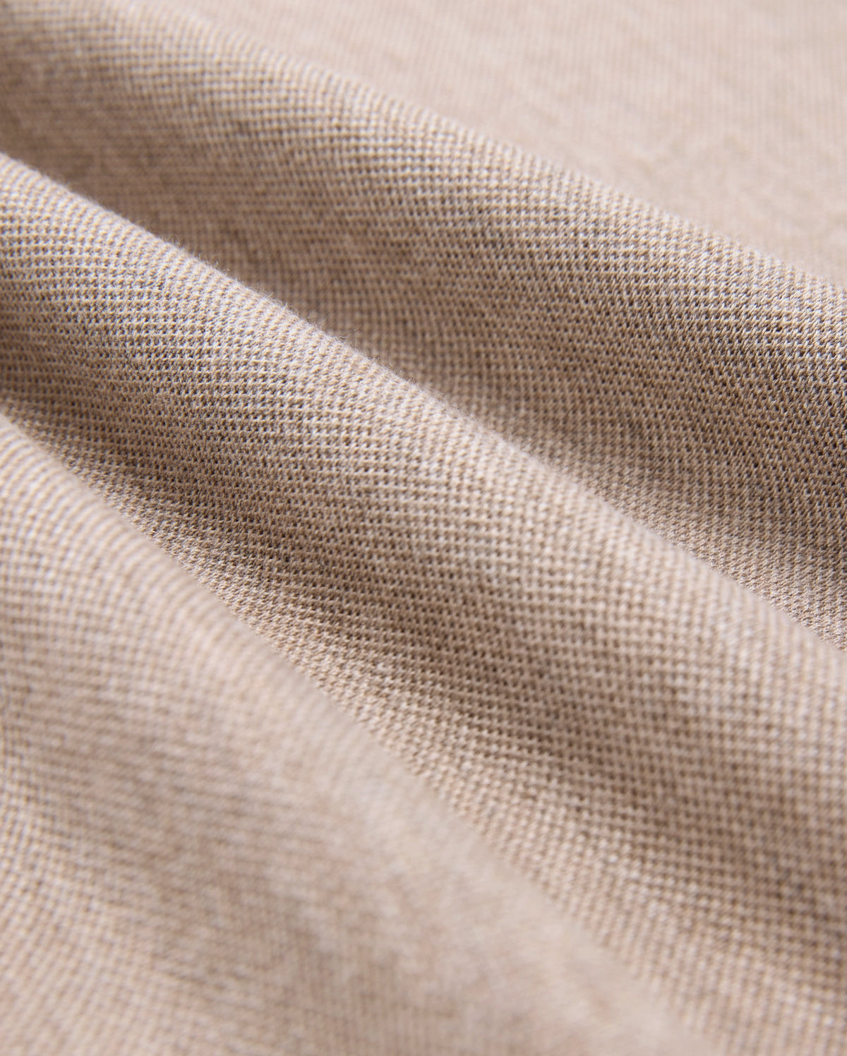 Close-up of beige Pima cotton fabric showcasing its fine weave and texture. The material is slightly draped, forming gentle folds that highlight its softness and quality, making it look ideal for crafting a durable Psycho Bunny MENS JAMES PREMIUM PIQUE POLO SHIRT - B6K945D200.