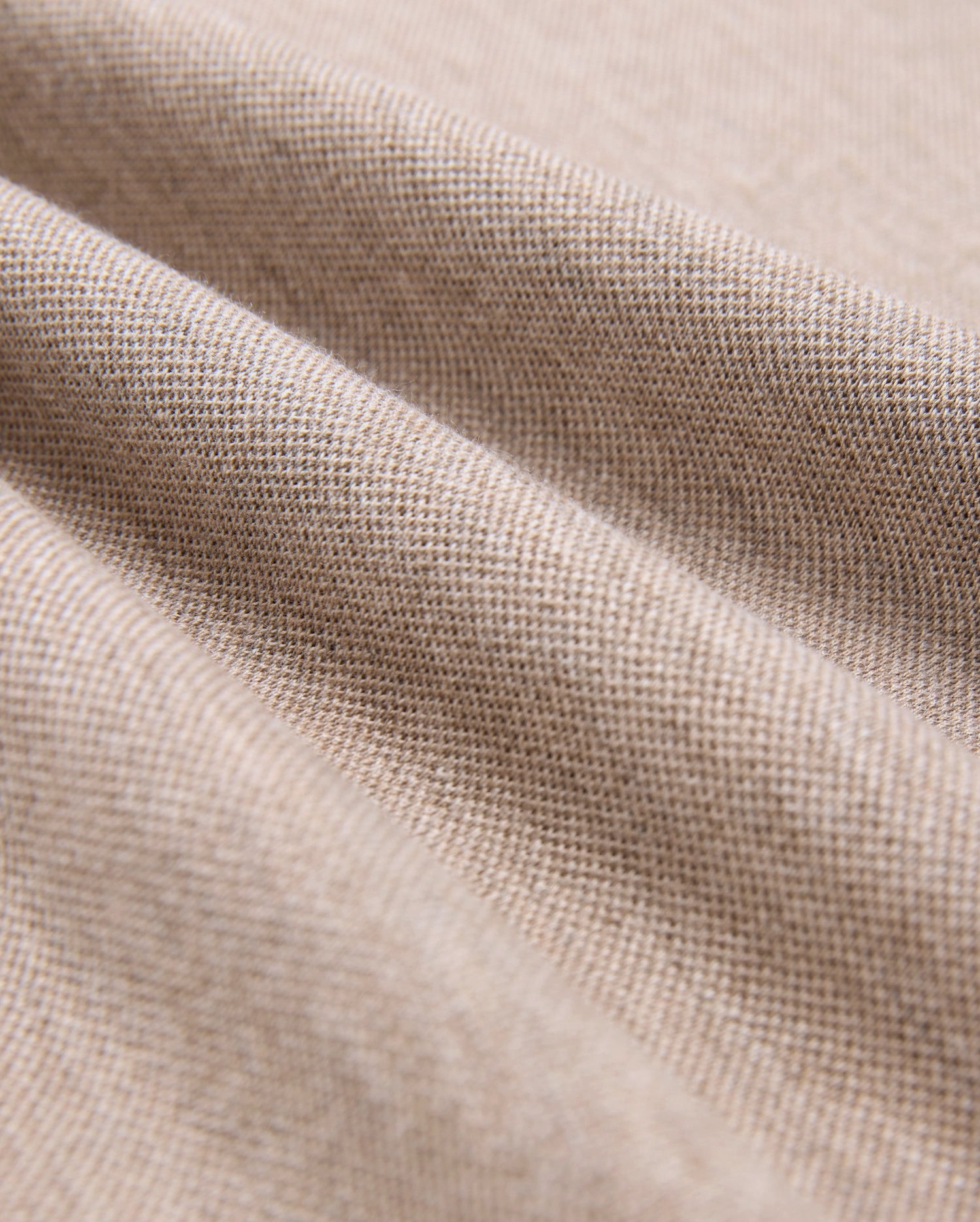 Close-up of beige Pima cotton fabric showcasing its fine weave and texture. The material is slightly draped, forming gentle folds that highlight its softness and quality, making it look ideal for crafting a durable Psycho Bunny MENS JAMES PREMIUM PIQUE POLO SHIRT - B6K945D200.