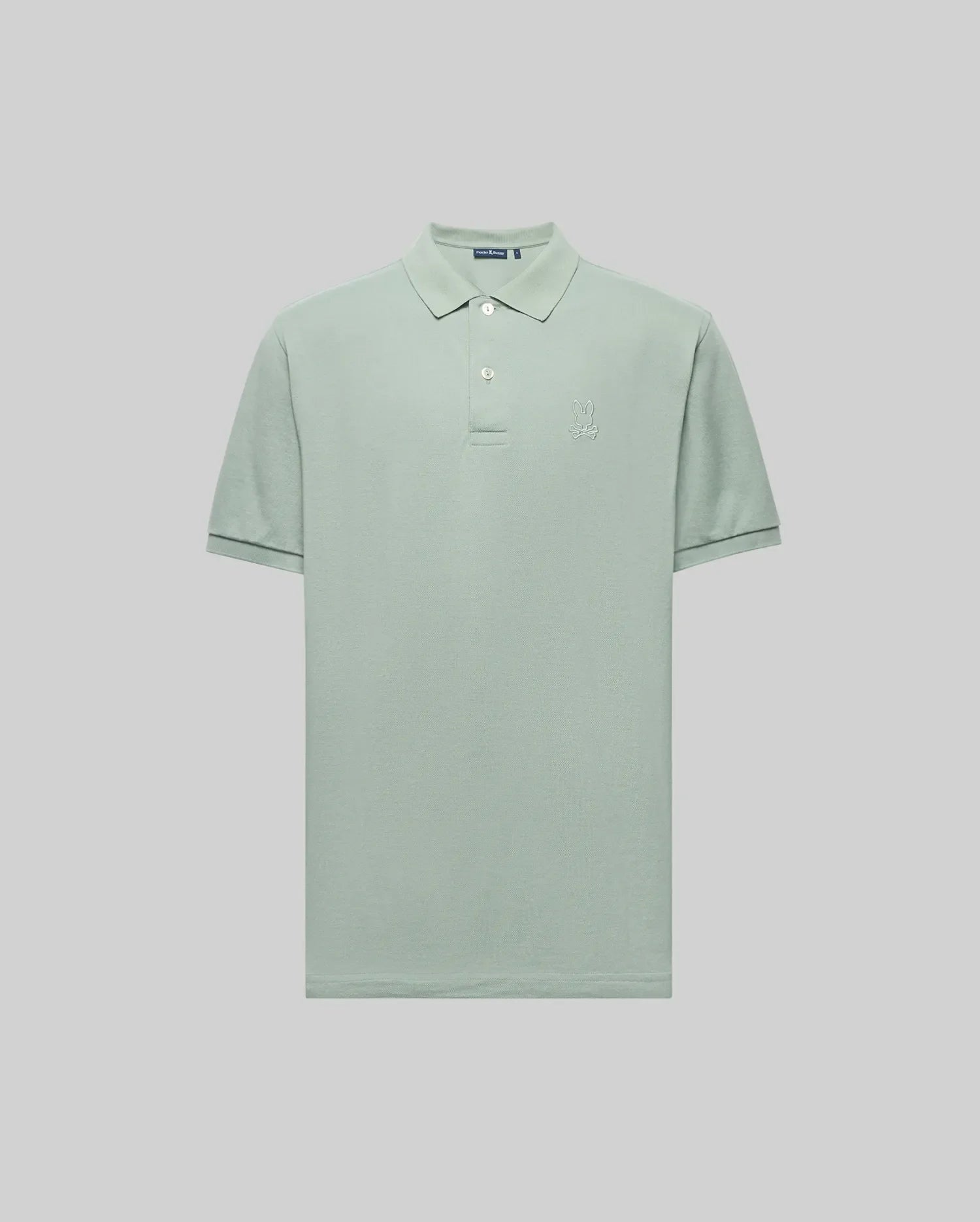 The Psycho Bunny MENS JAMES PREMIUM PIQUE POLO (B6K945D200) is a light green, short-sleeve shirt in soft Pima cotton with a crease-resistant collar, two-button placket, and subtle left chest logo, shown against a light grey background.