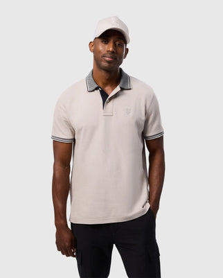 A man in a white hat, sporting the Psycho Bunny MENS MALTON PIQUE POLO SHIRT - B6K950D200, made from Pima cotton with a subtle diamond pique pattern.