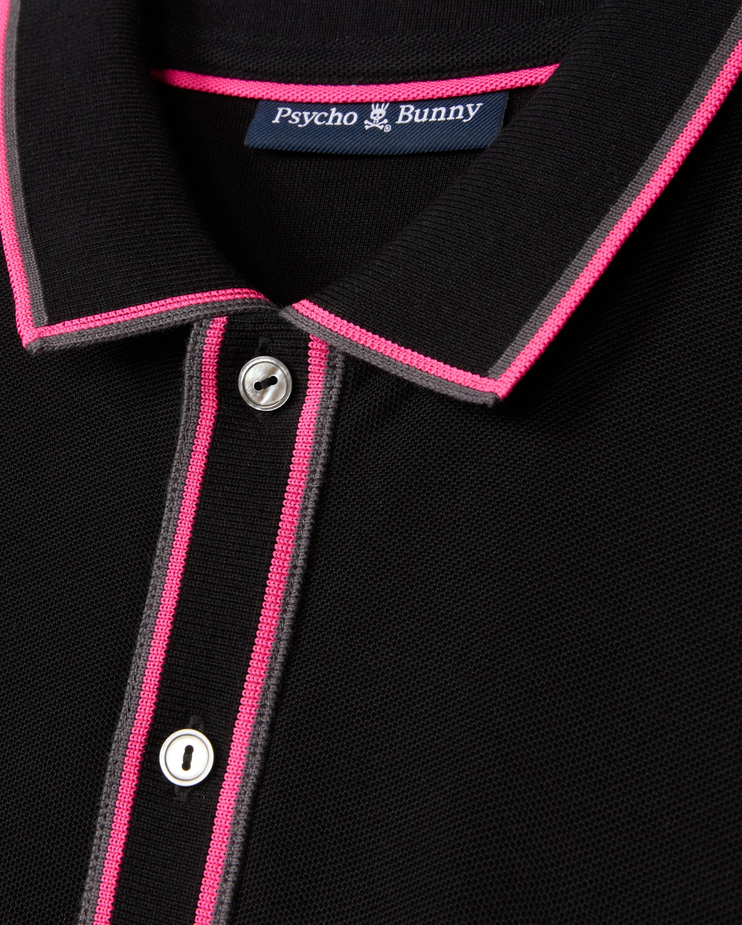 Close-up of the MENS KENT PIQUE POLO SHIRT - B6K951D200, showcasing a chic black design with pink and gray accents on the collar and button placket. Featuring two visible buttons and an interior "Psycho Bunny" label, this shirt is crafted from comfortable pique fabric, ideal for those who value fashion-forward elegance.