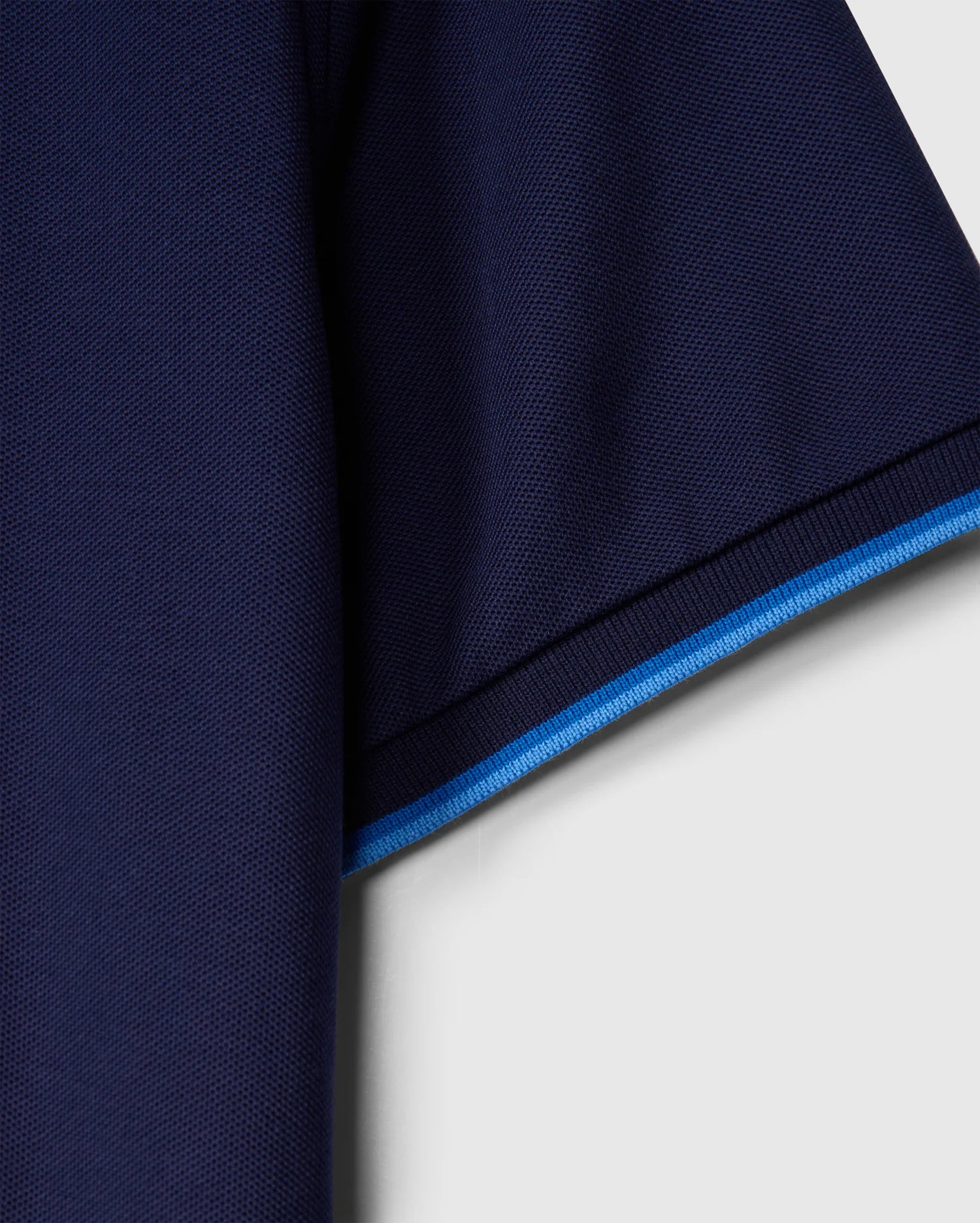 Close-up of the Psycho Bunny MENS KENT PIQUE POLO SHIRT - B6K951D200, showcasing the dark blue fabric sleeve with a light blue trim. The Pima cotton texture is visible against a light background.