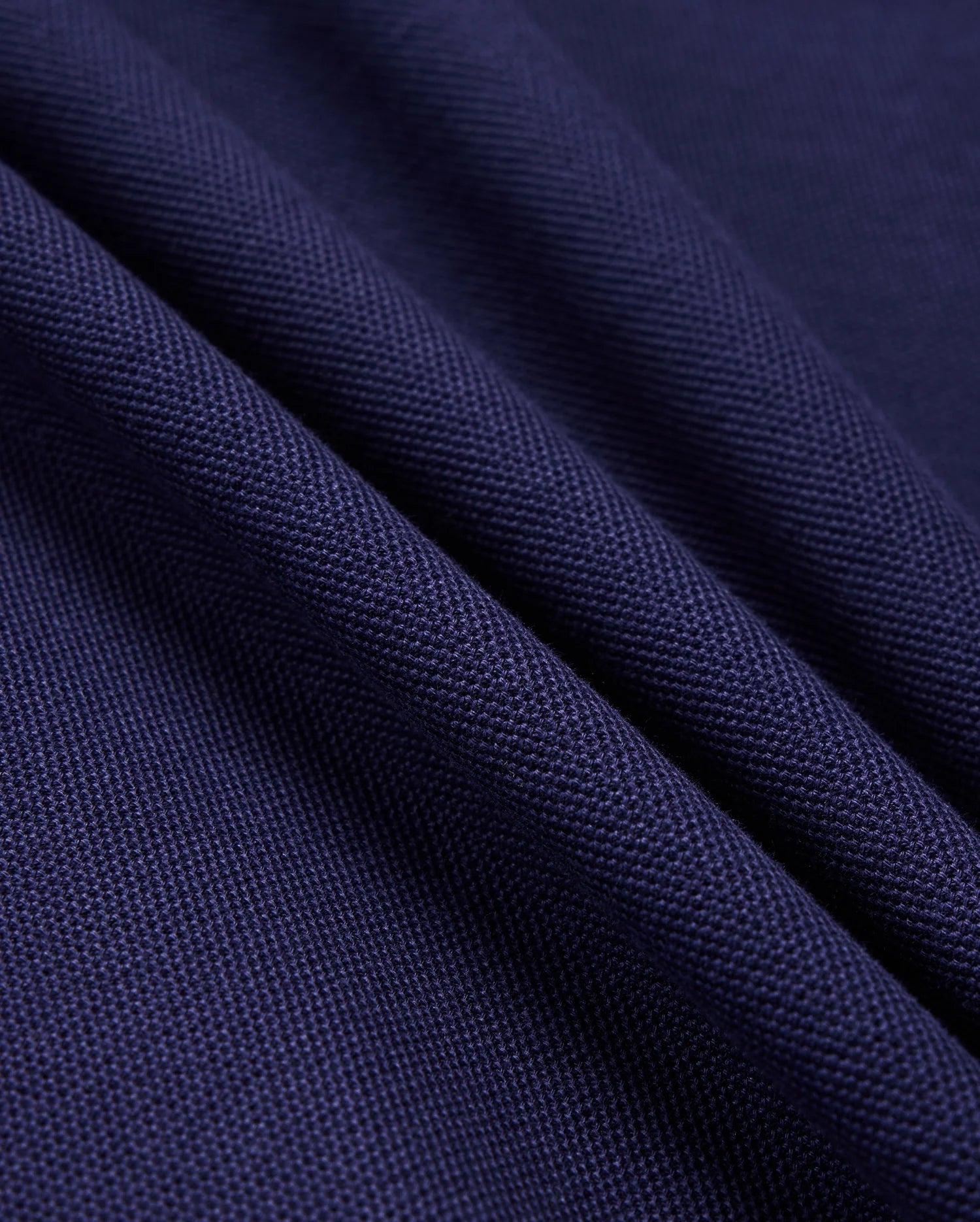 Close-up of folded fabric from the Psycho Bunny Men's Kent Pique Polo Shirt (B6K951D200) in dark blue, highlighting its textured, knit-like surface and stylish detail.