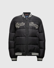 Introducing the MENS FRASER FASHION PUFFER - B6N338E200 by Psycho Bunny: a black puffer jacket adorned with white embroidered "Psycho Bunny" text on the front. This lightweight men's coat features a striped collar, cuffs, and hem, along with a convenient front zip closure. Its casual and sporty design makes it an ideal choice for any men's fashion enthusiast.