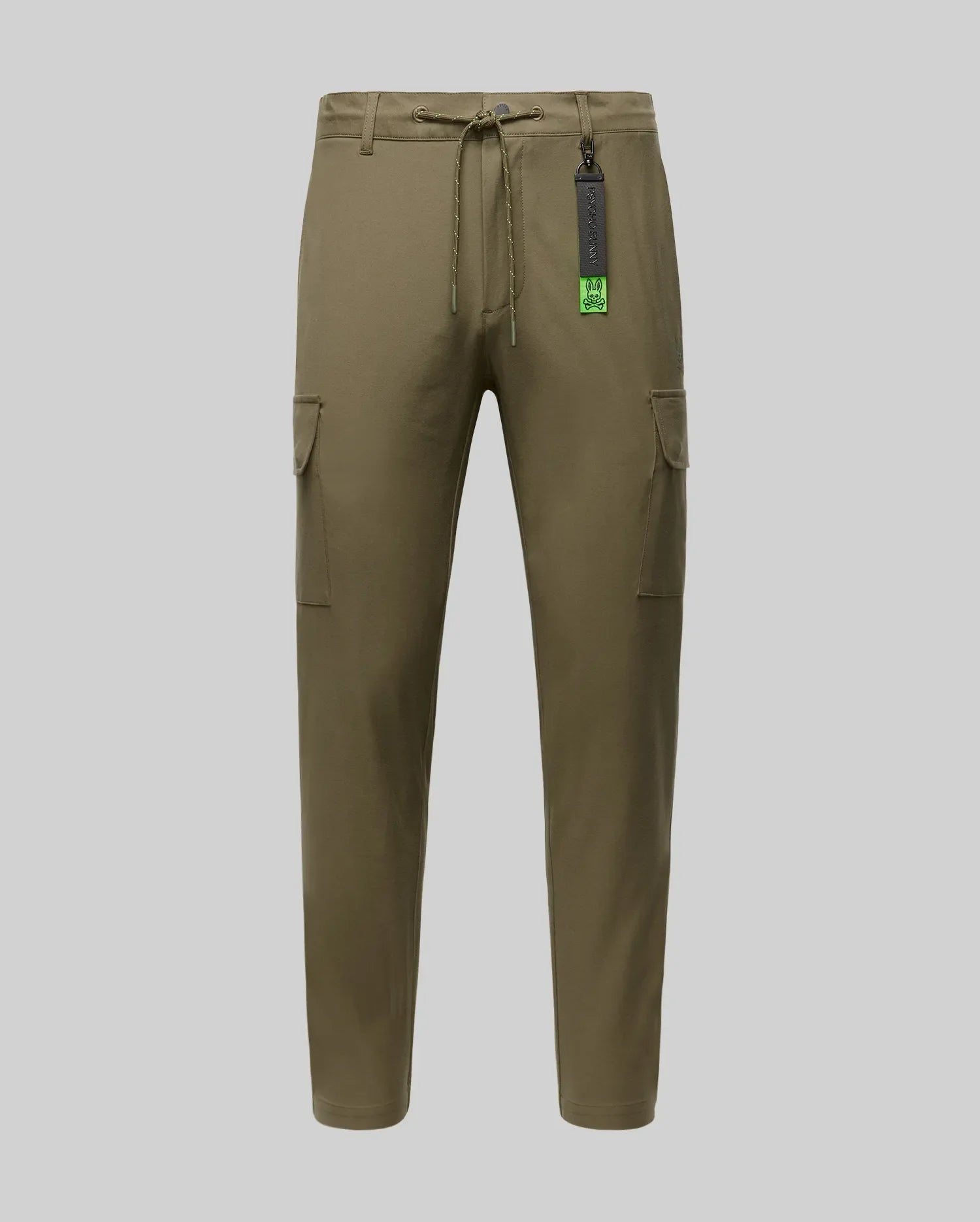 The Psycho Bunny MENS LLOYD CARGO JOGGER (B6P159B200) features khaki green fabric, a drawstring waist, side pockets, and a black tag near the waistband, shown on a plain light grey background.