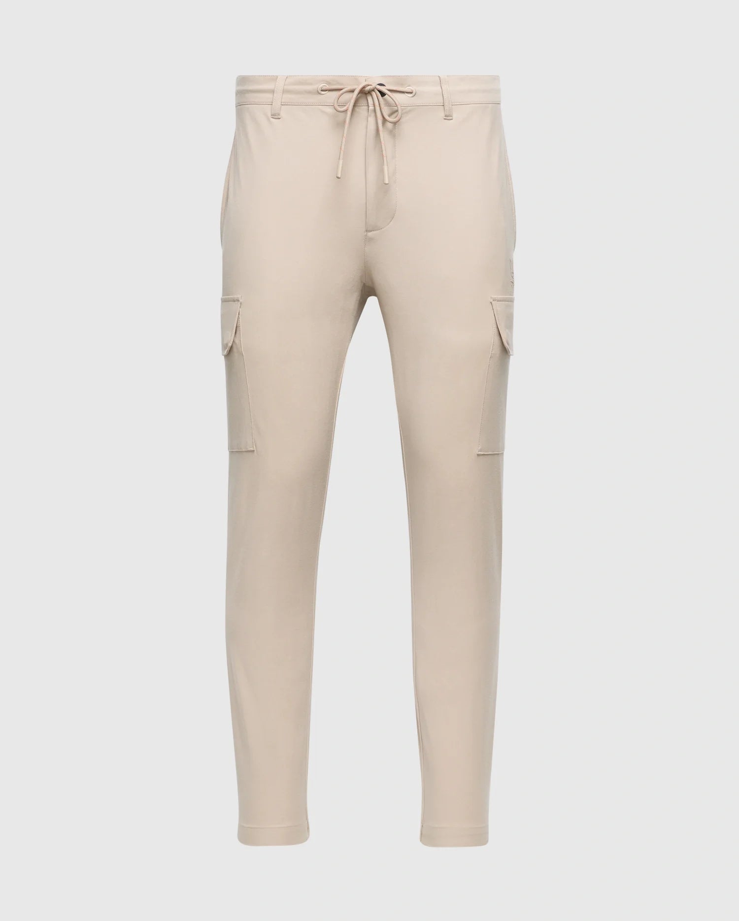 The MENS LLOYD CARGO JOGGER - B6P159B200 by Psycho Bunny is a pair of slim-fit beige cargo jogger pants, featuring tapered legs, an elastic waistband with a drawstring, two side pockets, and two cargo pockets on the thighs. These joggers are adorned with a subtle silicone branded detail.