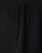 Close-up of the MENS LEVY ESSENTIAL FLEECE SWEATPANT - B6P721D200 by Psycho Bunny, showcasing black cotton sweatpants with an elastic waistband. The waistband features a matching black drawstring tied in a simple bow at the center. The texture of the fabric is visible, indicating comfort and durability, making them perfect for casual wear.