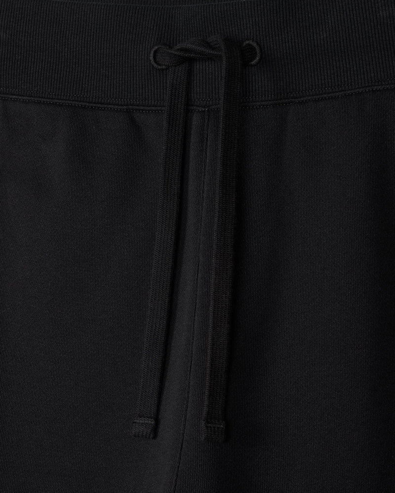 Close-up of the MENS LEVY ESSENTIAL FLEECE SWEATPANT - B6P721D200 by Psycho Bunny, showcasing black cotton sweatpants with an elastic waistband. The waistband features a matching black drawstring tied in a simple bow at the center. The texture of the fabric is visible, indicating comfort and durability, making them perfect for casual wear.