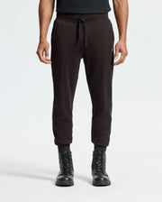 A person wearing Psycho Bunny's MENS LEVY ESSENTIAL FLEECE SWEATPANT (B6P721D200), made from 100% cotton, paired with black lace-up boots, standing against a plain white background.