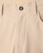 Close-up of the beige Psycho Bunny MENS MAVERICK 10K PANT - B6P788D200 showcasing a waistband with belt loops, a dark button, and a front pocket. The fabric appears smooth and is neatly stitched, offering four-way stretch for comfort. The stitching and design provide a casual yet tailored look.