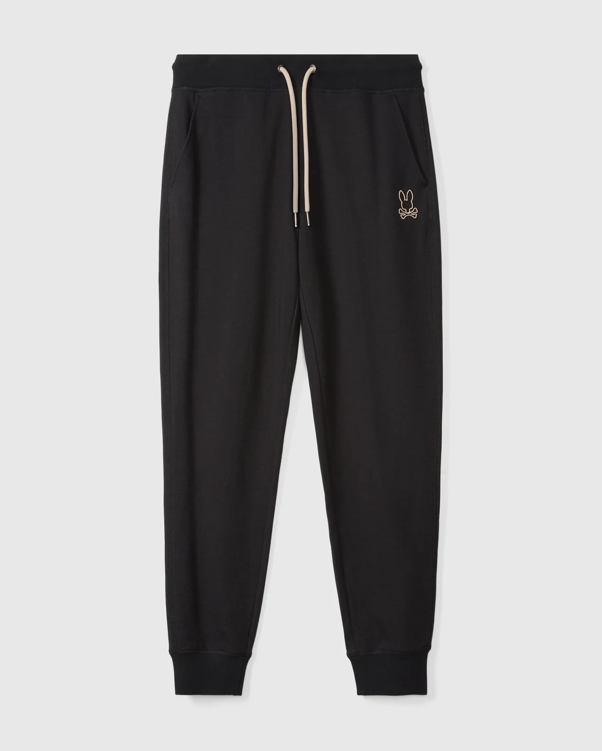 Psycho Bunny's MENS JAMES PREMIUM SWEATPANT - B6P791D200 features black jogger pants with a ribbed waistband and a beige drawstring. Crafted from a soft cotton-blend for ultimate comfort, these premium bottoms include side pockets and ribbed cuffs at the ankles. A small embroidered bunny logo adorns the left thigh. The joggers are photographed on a plain white background.