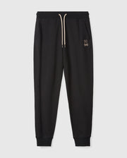 Psycho Bunny's MENS JAMES PREMIUM SWEATPANT - B6P791D200 features black jogger pants with a ribbed waistband and a beige drawstring. Crafted from a soft cotton-blend for ultimate comfort, these premium bottoms include side pockets and ribbed cuffs at the ankles. A small embroidered bunny logo adorns the left thigh. The joggers are photographed on a plain white background.