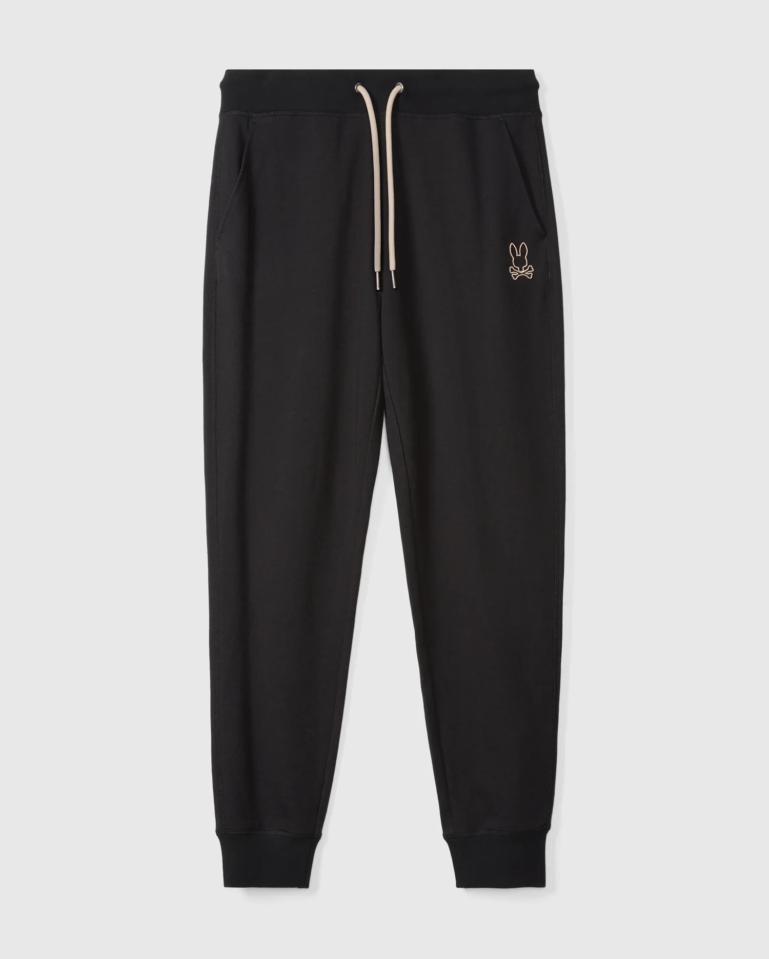 Psycho Bunny's MENS JAMES PREMIUM SWEATPANT - B6P791D200 features black jogger pants with a ribbed waistband and a beige drawstring. Crafted from a soft cotton-blend for ultimate comfort, these premium bottoms include side pockets and ribbed cuffs at the ankles. A small embroidered bunny logo adorns the left thigh. The joggers are photographed on a plain white background.