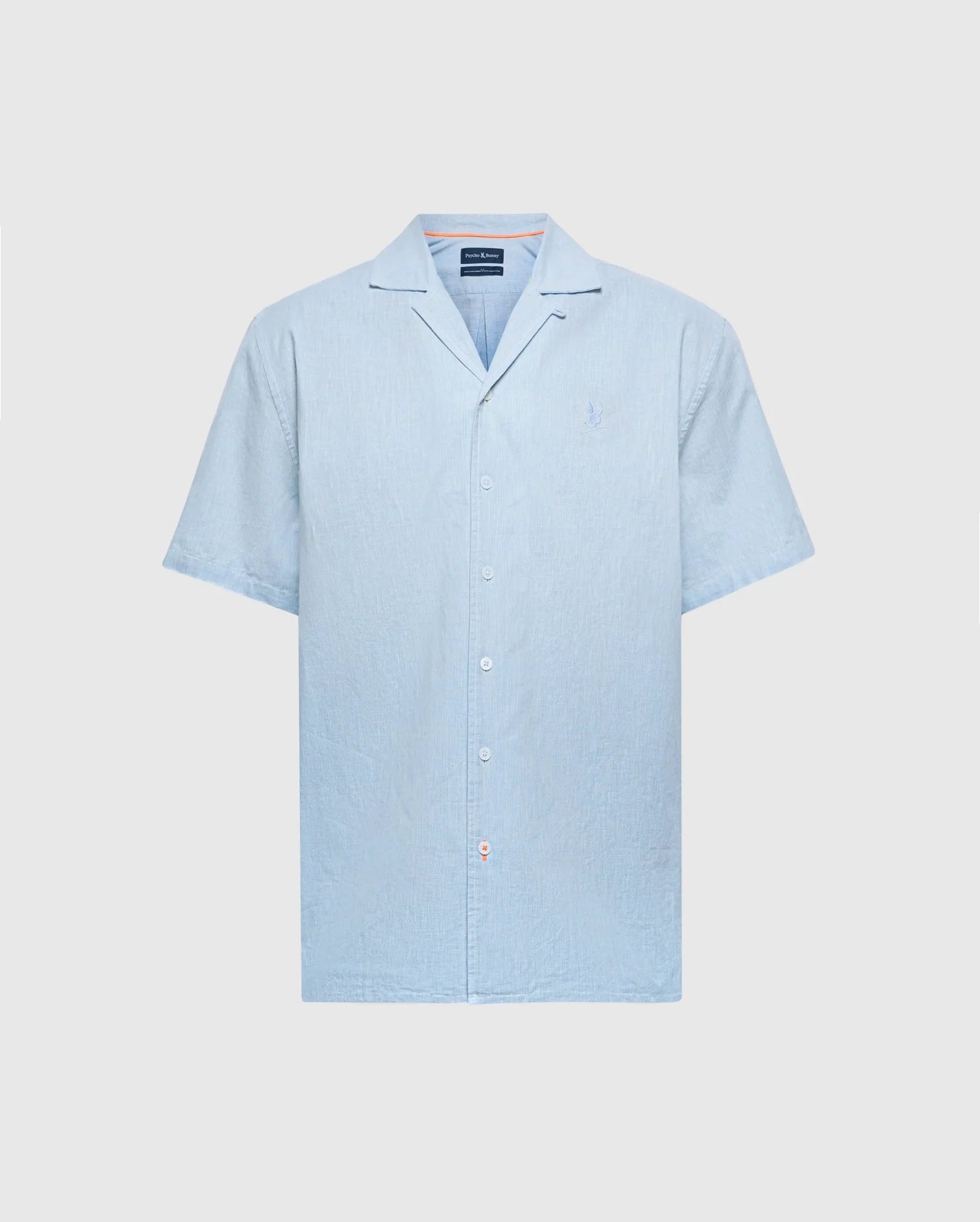The Psycho Bunny MENS COBAR WOVEN SHIRT (B6Q522F200) is a light blue, short-sleeve linen blend shirt with a camp collar, subtle texture, and tonal logo embroidery on the left chest, shown on a white background.