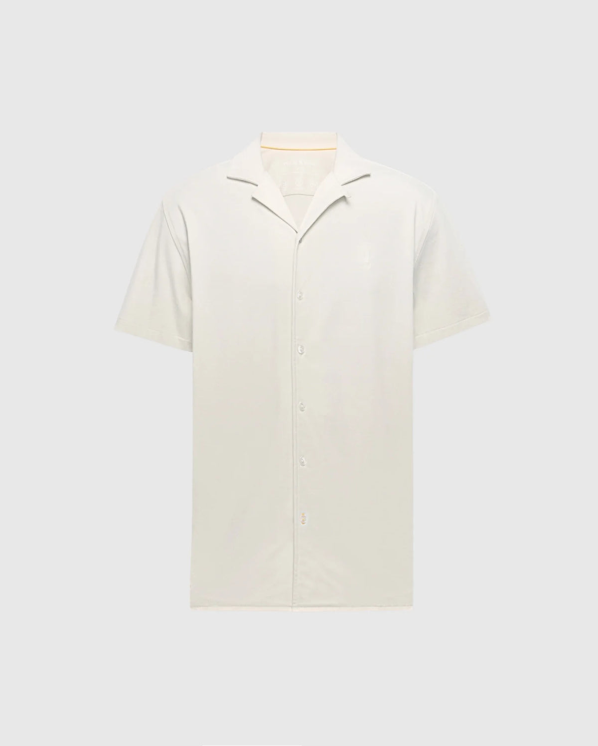 The Psycho Bunny MENS BRYAN CAMP COLLAR SHORT SLEEVE SHIRT - B6Q581F200, in light beige, features a classic collar and white buttons. Crafted from a Pima Cotton Blend, this shirt offers a soft feel for ultimate comfort and is displayed against a gray background highlighting its clean design.