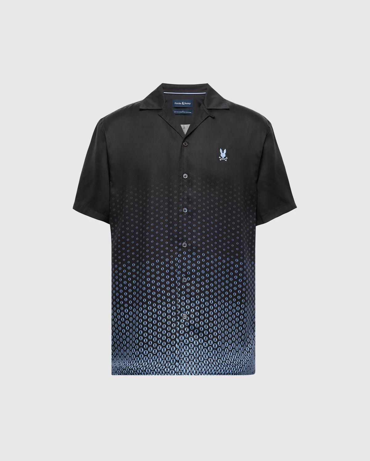 Psycho Bunny's MENS BENDIGO TENCEL SHIRT - B6Q627F200 is a short-sleeve black button-up with a blue ombre dot pattern at the bottom. Made from soft Tencel, it features a camp collar for a casual look and has a small emblem on the left chest.