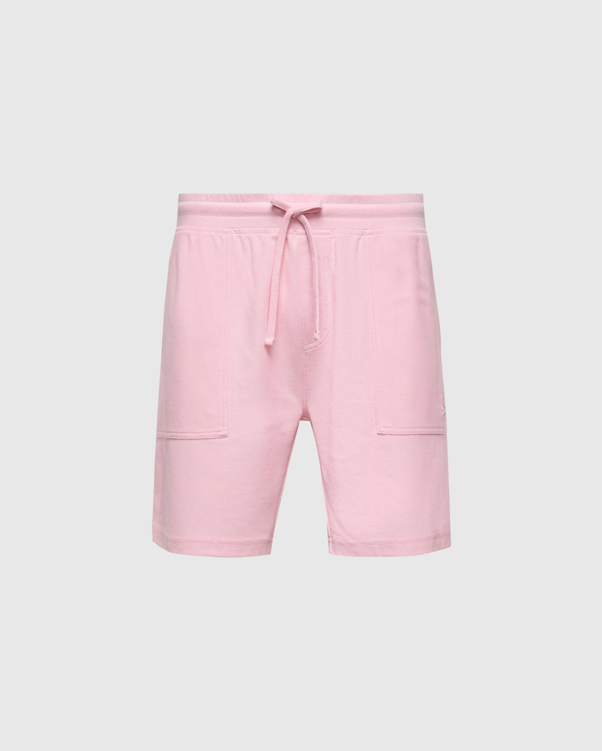 The MENS TAYLOR LIGHT PIQUE SWEATSHORT - B6R344F200 by Psycho Bunny pairs pink shorts with a drawstring waistband against a gray background. Made from lightweight Pima cotton, they offer knee-length style, side pockets, and casual-chic appeal for everyday wear.