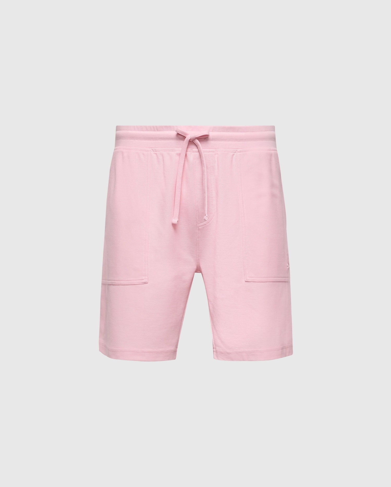 The MENS TAYLOR LIGHT PIQUE SWEATSHORT - B6R344F200 by Psycho Bunny pairs pink shorts with a drawstring waistband against a gray background. Made from lightweight Pima cotton, they offer knee-length style, side pockets, and casual-chic appeal for everyday wear.