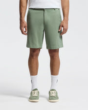 A person wears the Psycho Bunny MENS SHIRO KNIT HONEYCOMB SHORT - B6R585F200, paired with piqué sneakers and crisp white socks against a plain white background, showcasing just their lower half.