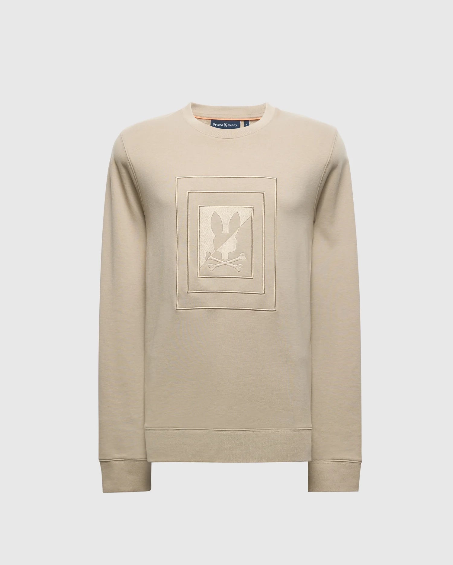 The MENS OAK CITY CREW NECK - B6S274E200 by Psycho Bunny is a beige, lightweight sweatshirt with a crew neckline and ribbed cuffs. It features a raised embroidery square design on the front with an abstract graphic at the center.