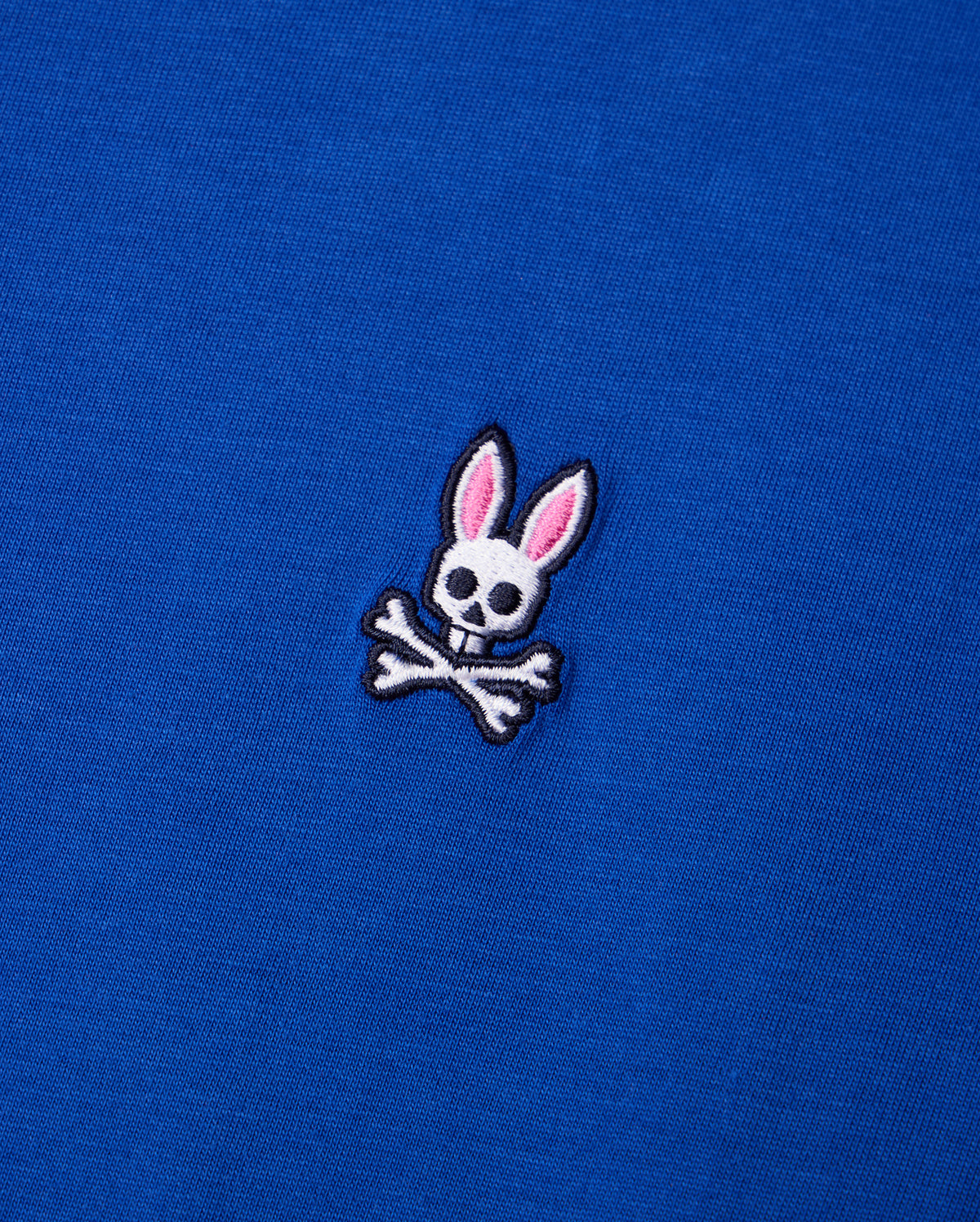 Crafted from luxurious Pima cotton, the Psycho Bunny MENS CLASSIC CREW NECK TEE - B6U014CRPC features a subtle embroidered logo of a rabbit skull with pink ears elegantly perched above crossed bones, creating a striking contrast against the blue fabric.