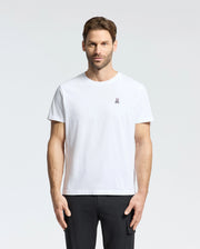 A person with short brown hair and a beard wears the Psycho Bunny MENS CLASSIC CREW NECK TEE - B6U014CRPC, made of 100% Pima cotton with an embroidered logo on the chest. They stand against a light gray backdrop, highlighting the comfy fit perfect for big and tall enthusiasts.