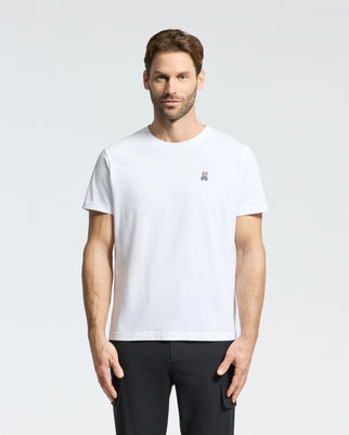 A person with short brown hair and a beard wears the Psycho Bunny MENS CLASSIC CREW NECK TEE - B6U014CRPC, made of 100% Pima cotton with an embroidered logo on the chest. They stand against a light gray backdrop, highlighting the comfy fit perfect for big and tall enthusiasts.