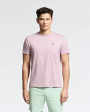 Wearing a Psycho Bunny MENS CLASSIC CREW NECK TEE in light pink, made from 100% pima cotton with a chest logo, paired with mint green shorts, the person stands against a white background.