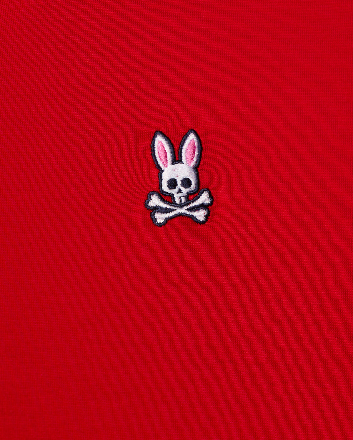 This men's v-neck tee, by Psycho Bunny, features a small emblem of a bunny skull with pink ears and crossbones embroidered on its bright red fabric. It's crafted from premium Pima cotton for exceptional quality. The product is named MENS CLASSIC V NECK TEE - B6U100CRPC.
