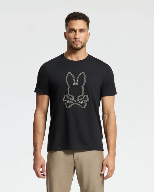 A man models the Psycho Bunny Men's Monarc Front Bunny Graphic Tee (B6U211E200), a black Pima cotton T-shirt, pairing it stylishly with khaki pants against a plain white background.