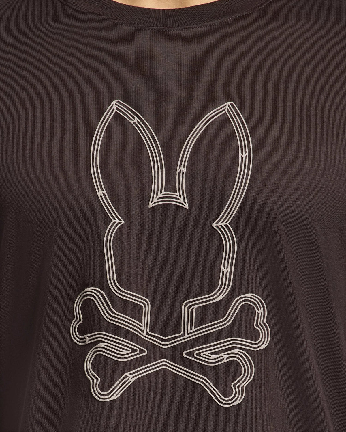 The Psycho Bunny MENS MONARC FRONT BUNNY GRAPHIC TEE - B6U211E200 is a fun black shirt crafted from 100% Pima cotton, showcasing a white rabbit head with long ears above crossed bones, echoing a quirky skull-and-crossbones design.