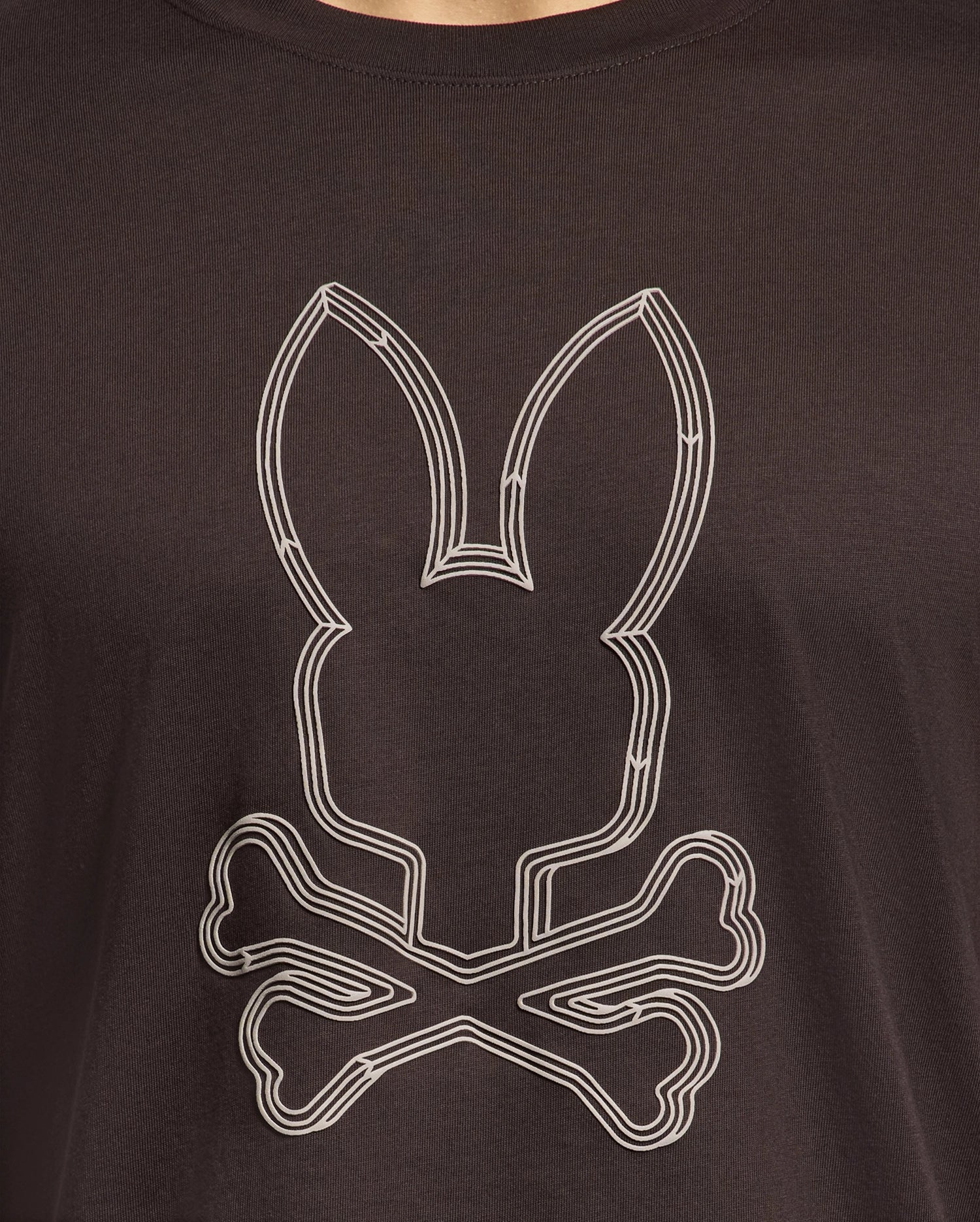 The Psycho Bunny MENS MONARC FRONT BUNNY GRAPHIC TEE - B6U211E200 is a fun black shirt crafted from 100% Pima cotton, showcasing a white rabbit head with long ears above crossed bones, echoing a quirky skull-and-crossbones design.
