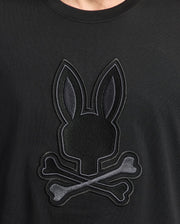 Close-up of the Psycho Bunny MENS NEW CASTLE EMBROIDERED GRAPHIC TEE in soft Pima cotton, featuring an embroidered bunny head with long ears above crossed bones, resembling a skull-and-crossbones design.
