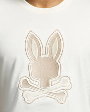 Close-up of the Psycho Bunny Mens New Castle Embroidered Graphic Tee, made from Pima cotton, featuring an embroidered Bunny design. The stylish bunny head with long ears is set above two crossed bones, echoing a skull and crossbones motif.