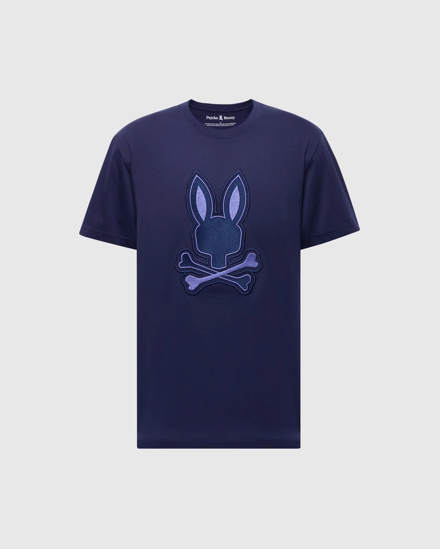 The Psycho Bunny Men's New Castle Embroidered Graphic Tee, made from soft Pima cotton, features a navy blue design with an embroidered Bunny emblem of a stylized rabbit head and ears above crossed bones.
